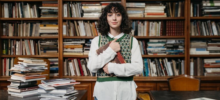 A student in a library holding a book