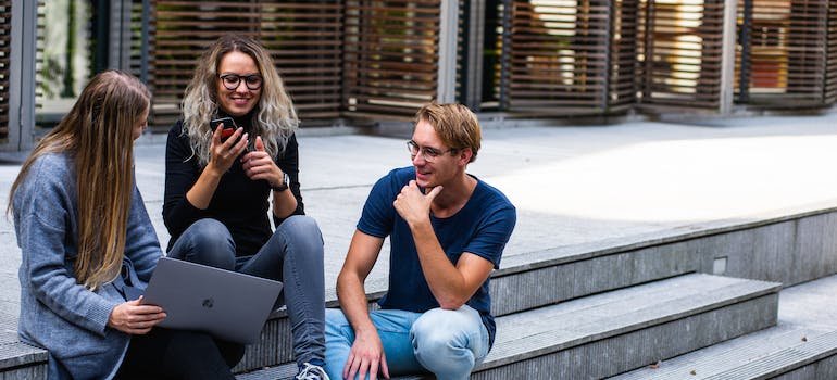 Three young people sitting together and using a laptop