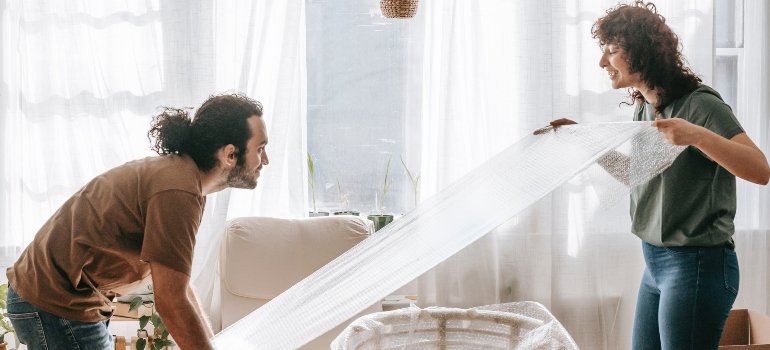 a couple wrapping a chair in bubble wrap so they can have a stress-free move from Bronx to Manhattan