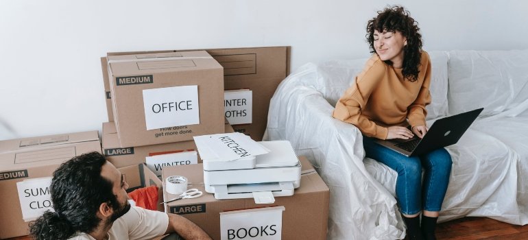 A couple surrounded with moving boxes at their new home after moving between NYC boroughs