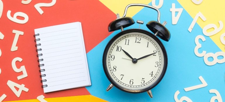 A clock on a colorful table nd a notebook.