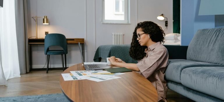 Woman using her laptop to search the web, papers on the desk in front of her