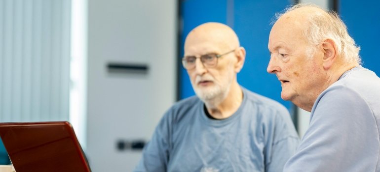 Two elderly men reading about self storage that helps elderly residents