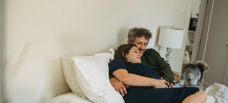 A couple lying in a bed and talking about moving.