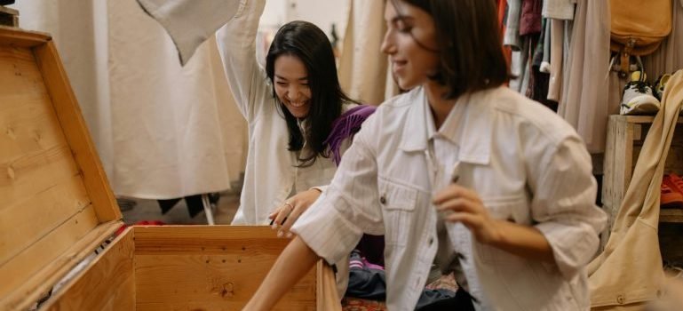Two women packing clothes and talking about storage unit myths explained