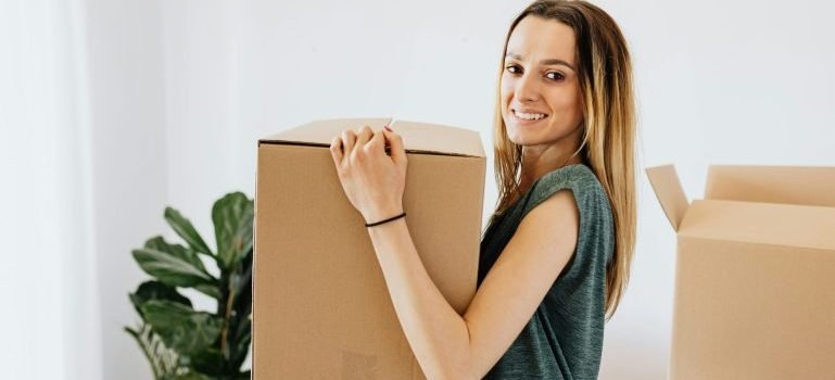 Woman holding a cardboard box and smiling.
