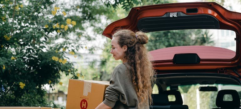 A woman carrying a cardboard moving box