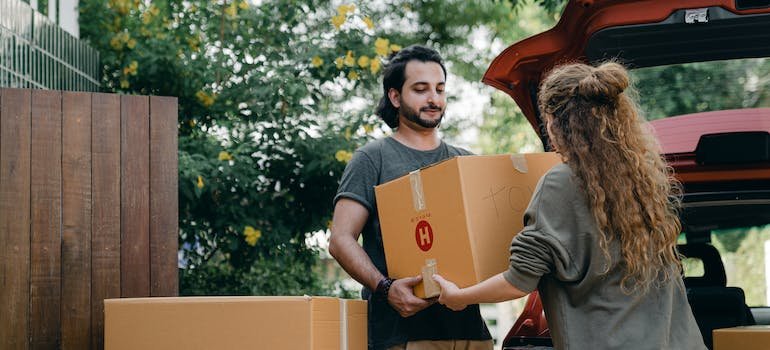 A couple handling their moving boxes after making sure their moving day survival kit is ready.
