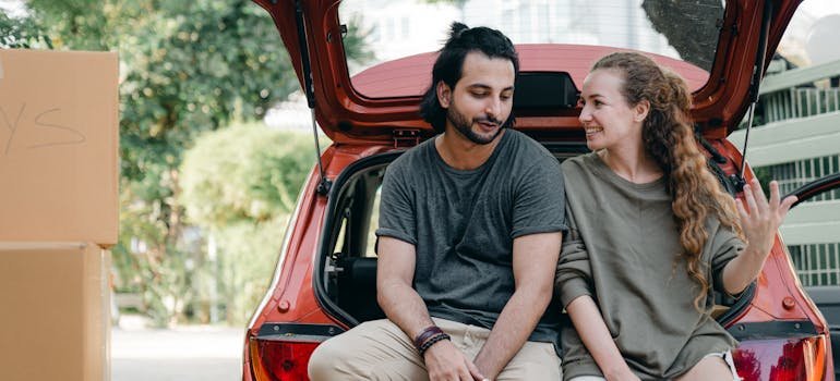 A couple sitting in the trunk of a car.