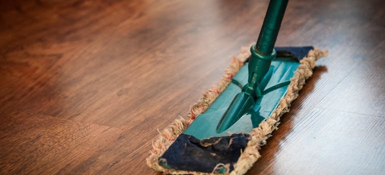 A mop on the wooden floor to do the cleaning after you declutter your home for sale.