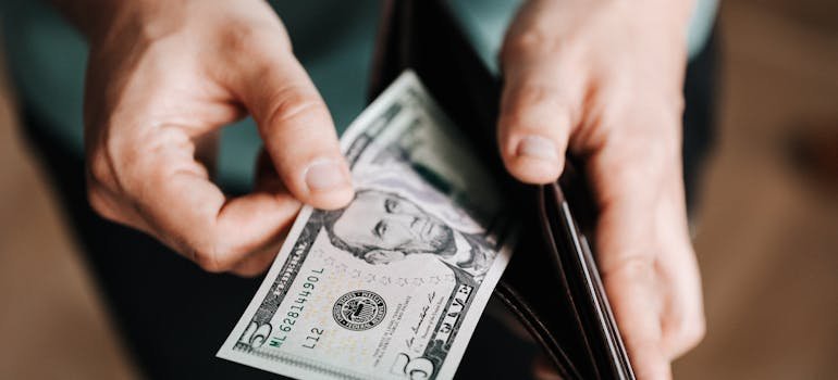 A man taking out a 5-dollar bill out of his wallet.
