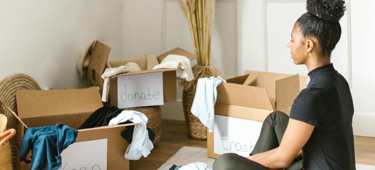 A woman person decluttering her home and organzing her items into three labeled boxes.