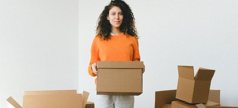 A young woman is handling some moving boxes while trying to relocate in less than a week using portable storage.