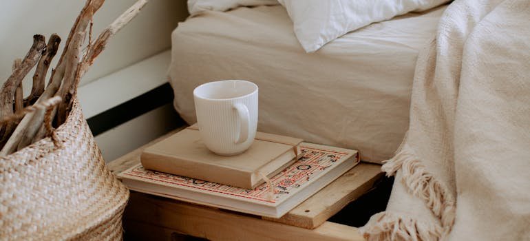 Books and a cup next to the bed.