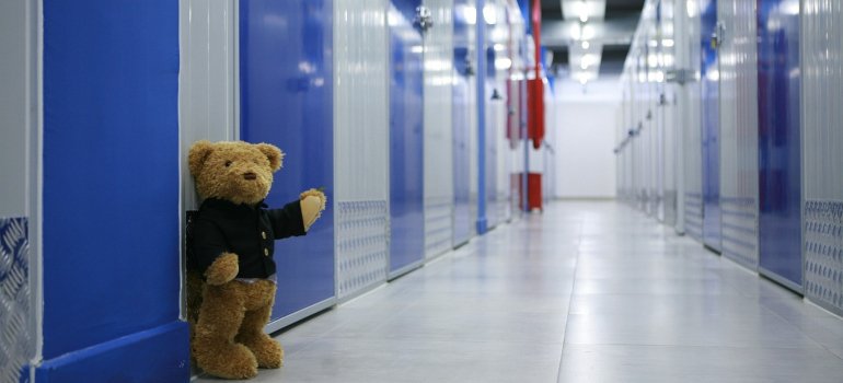 A teddy bear in the corridor of a storage facility.