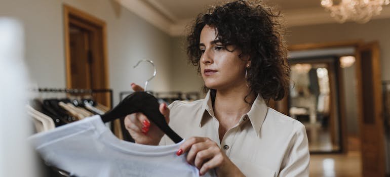 A woman putting away clothes on hangers.