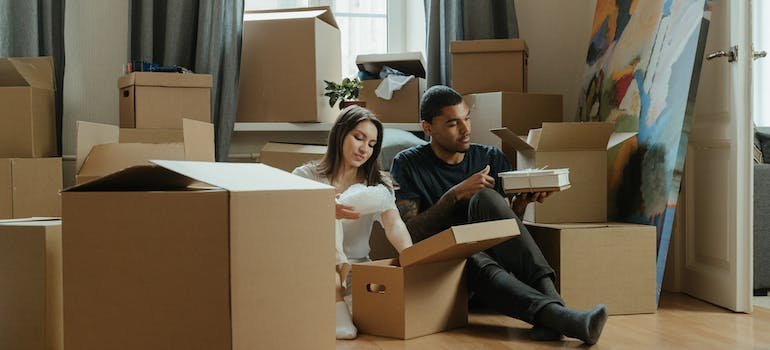A couple surrounded with moving cardboard boxes thinking about storage solutions for newlywed couples in Manhattan.