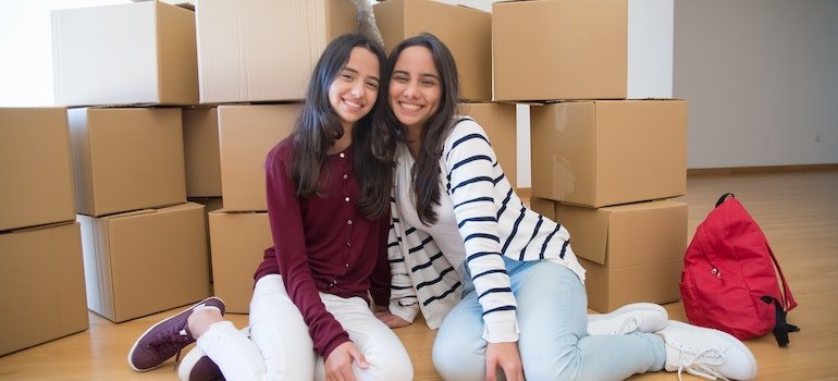 Two girls sitting next to some piles of cardboard boxes before renovating your Bronx apartment