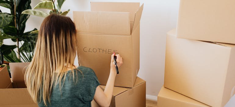 A woman writing down on a cardboard box
