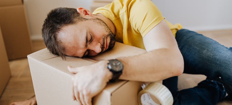A man feeling tired and lying on a cardboard box after renovating your Bronx apartment.