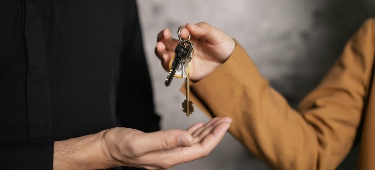 A person giving a bundle of keys to another person.
