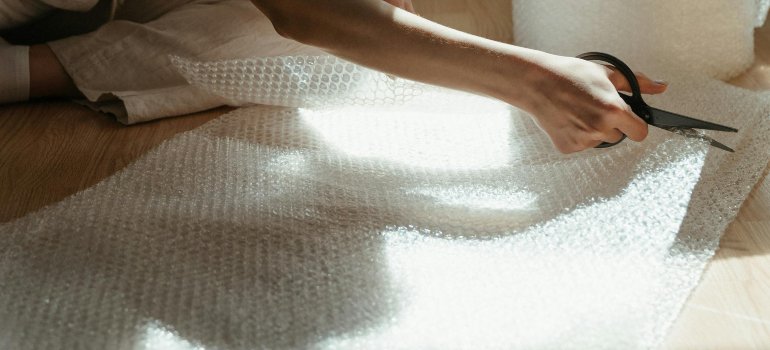 A woman who cuts bubble wrap and preparing office furniture for long-term storage