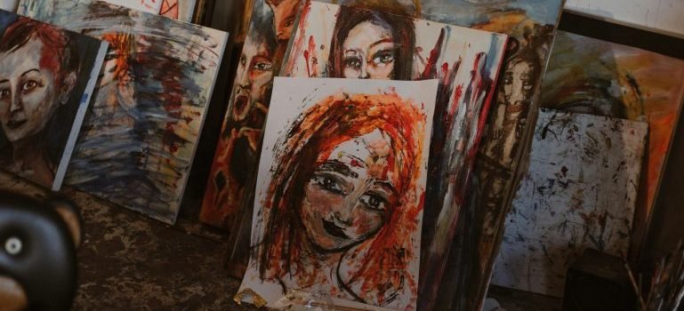 Drawings and paintings placed on the floor in a storage unit.