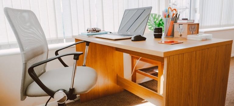 A white rollingarm chair besides a desk.