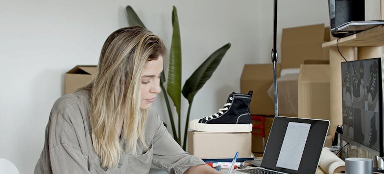 A woman sitting at a desk and writing a list of the items NYC businesses frequently keep in storage.