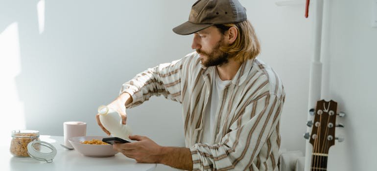 A man pouring milk and reading on his cell phone about protecting musical instruments in storage