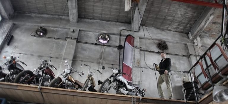 A man standing in a storage with motobikes.