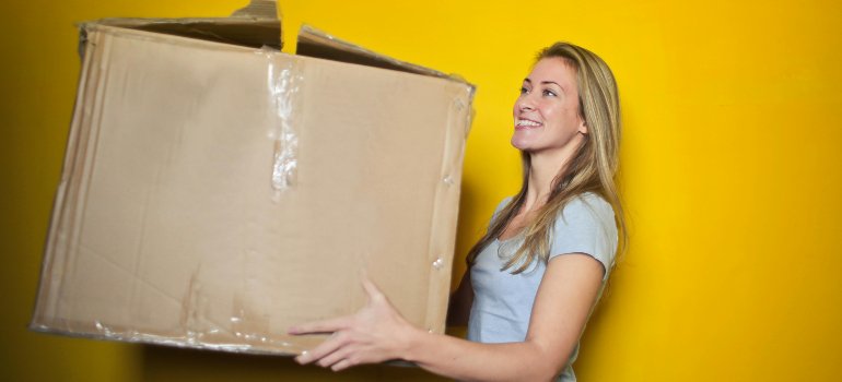 A girlcarrying a cardboard box for packing and then storing lampshades and chandeliers