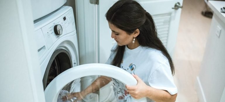 A woman opening a washing machine.