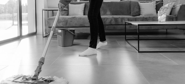 A person working on keeping a big home clean and organized by mopping the floor.