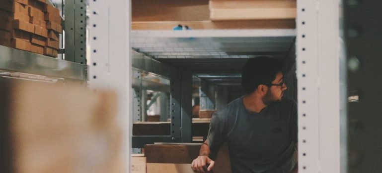 A man under a bunch of large shelves in storage which you can use if you want to be a considerate neighbor and tenant in Manhattan.