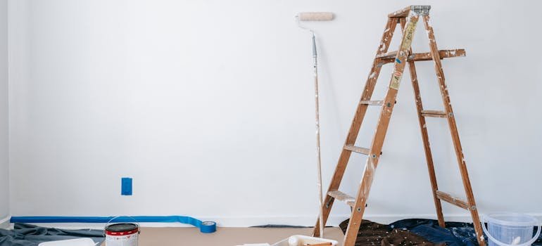 A ladder and a painting brush in the room.