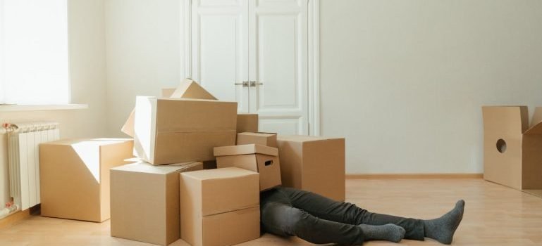 A man covered with cardboard boxes lying on the floor after he found out about warning signs of a storage scam.