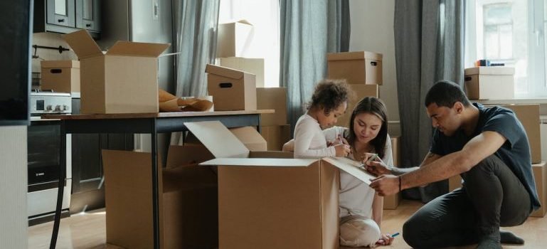 A family sitting on the floor and a lot of boxes.