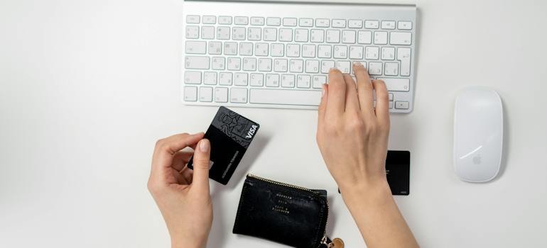 A person holding a debit card and typing.