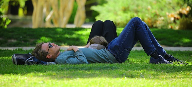 Two people lying on the grass in the park.