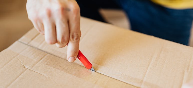A person cutting up a moving box.