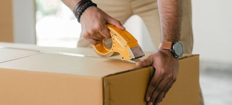 A man taping a big brown box.