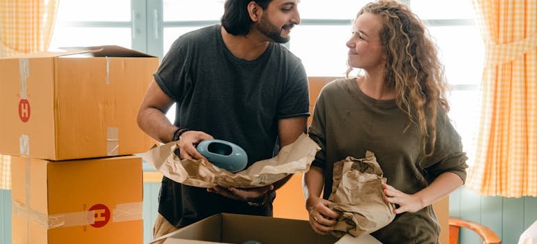 A man and a woman smiling to each other while packing.