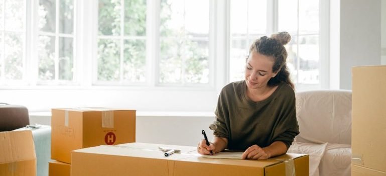A woman and boxes for packing after finding a cheap rental in Manhattan.