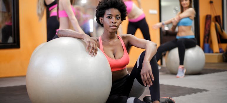 A woman sitting on the floor next to a large Pilates ball after moving to the Upper West Side.