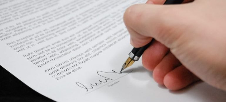 A man holding a pen and signing a paper.