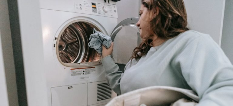 A woman loading clothes in a washing machine.