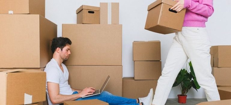 A man and woman surrounded with boxes because they need to maintain their Manhattan apartment clutter-free