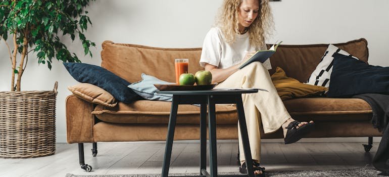 A woman sitting on a sofa and writing how to tackle spring cleaning in your storage space.