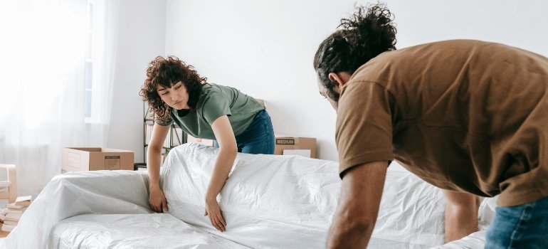 Two people packing and storing upholstered and leather furniture